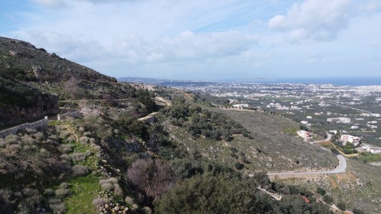 Drone perspective of hillside plot in Malaxa with expansive countryside and bay views