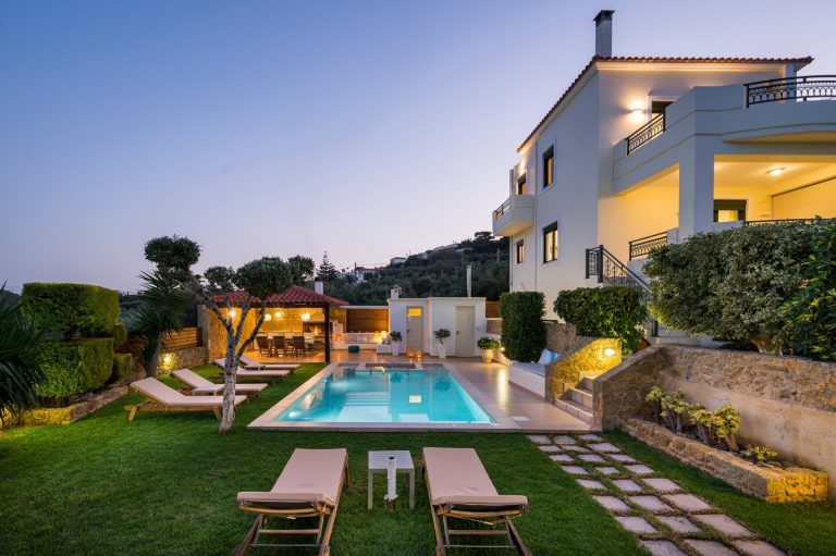 Exterior of luxury villa for sale in Afrata Crete with private swimming pool, pergola dining area and stone BBQ