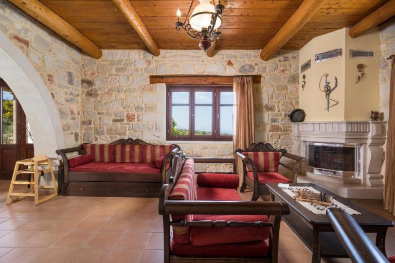 Cozy living room in Crete stone villa featuring fireplace and panoramic sea view windows