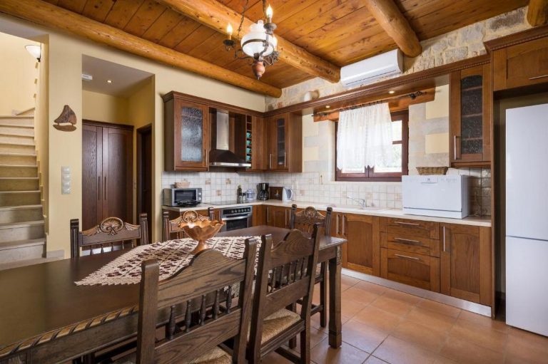 Open-plan fully equipped kitchen in Platanos home with traditional stone design