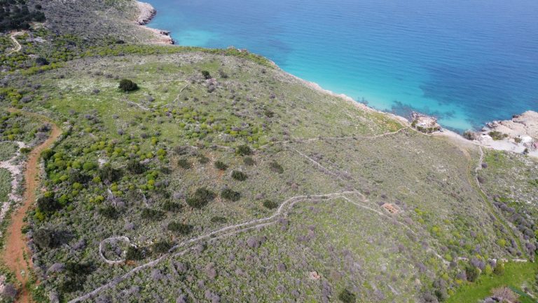 Sweeping Drone View of Seaside Property with Mountain Backdrop
